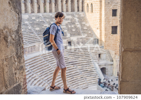 Man tourist explores Aspendos Ancient City. Aspendos acropolis city ruins, cisterns, aqueducts and old temple. Aspendos Antalya Turkey. turkiye 107909624