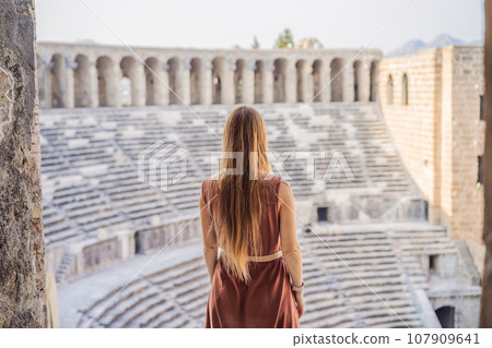 Woman tourist explores Aspendos Ancient City. Aspendos acropolis city ruins, cisterns, aqueducts and old temple. Aspendos Antalya Turkey. turkiye 107909641