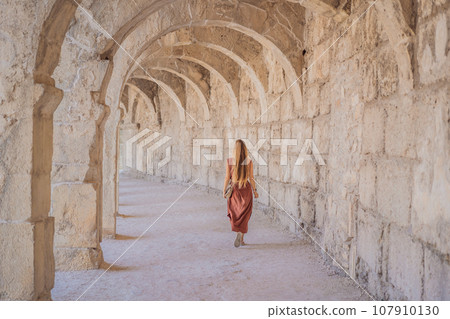 Woman tourist explores Aspendos Ancient City. Aspendos acropolis city ruins, cisterns, aqueducts and old temple. Aspendos Antalya Turkey. turkiye 107910130