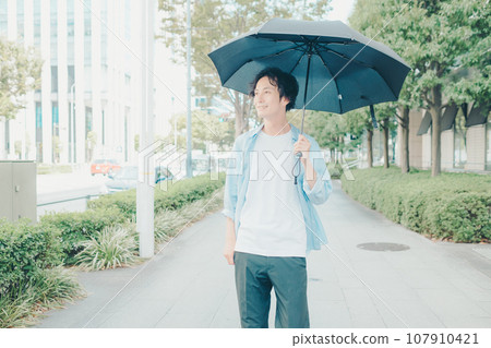 A man in his 30s holding a parasol A man in his 30s holding a parasol 107910421