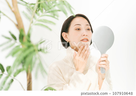 A woman watching a hand mirror A woman watching a hand mirror 107910648