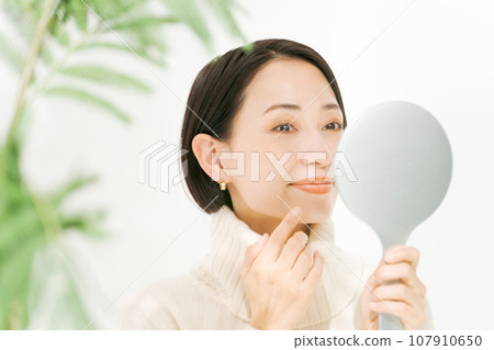 A woman watching a hand mirror A woman watching a hand mirror 107910650