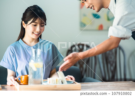 A young woman and a clerk in an apron taking brunch at a cafe A young woman and a clerk in an apron taking brunch at a cafe 107910802