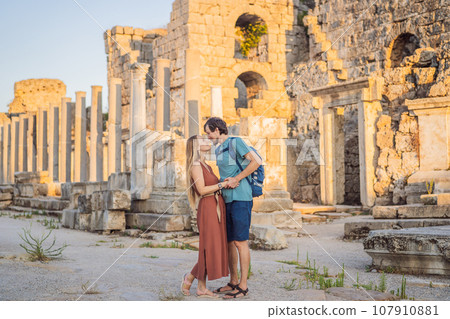 Loving couple of tourists at the ruins of ancient city of Perge near Antalya Turkey. Traveling with kids concept Loving couple of tourists at the ruins of ancient city of Perge near Antalya Turkey. Traveling with kids concept 107910881