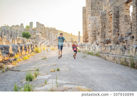 dad and son tourists at the ruins of ancient city of Perge near Antalya Turkey. Traveling with kids concept dad and son tourists at the ruins of ancient city of Perge near Antalya Turkey. Traveling with kids concept 107910899