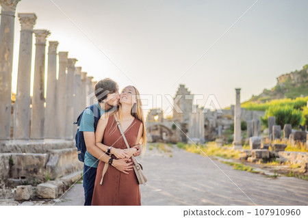 Loving couple of tourists at the ruins of ancient city of Perge near Antalya Turkey. Traveling with kids concept 107910960