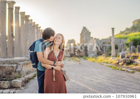Loving couple of tourists at the ruins of ancient city of Perge near Antalya Turkey. Traveling with kids concept Loving couple of tourists at the ruins of ancient city of Perge near Antalya Turkey. Traveling with kids concept 107910961