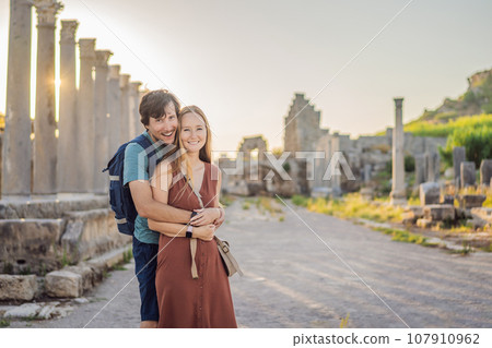Loving couple of tourists at the ruins of ancient city of Perge near Antalya Turkey. Traveling with kids concept Loving couple of tourists at the ruins of ancient city of Perge near Antalya Turkey. Traveling with kids concept 107910962