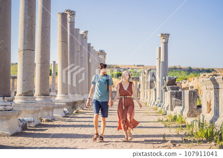 Loving couple of tourists at the ruins of ancient city of Perge near Antalya Turkey. Traveling with kids concept Loving couple of tourists at the ruins of ancient city of Perge near Antalya Turkey. Traveling with kids concept 107911041