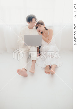 Couple relaxing while looking at a computer Couple relaxing while looking at a computer 107911241
