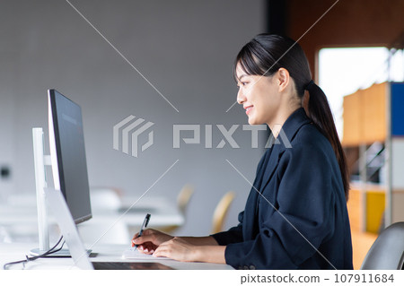 A woman taking notes while checking the monitor A woman taking notes while checking the monitor 107911684