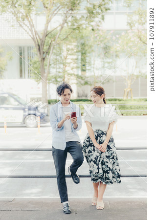 Men and women looking at smartphones on the street 107911892