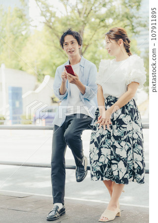 Men and women looking at smartphones on the street Men and women looking at smartphones on the street 107911895