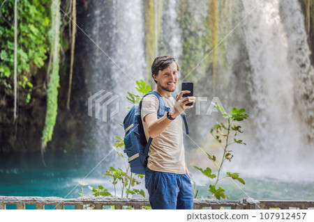 Man on the background of Duden waterfall in Antalya. Famous places of Turkey. Apper Duden Falls Man on the background of Duden waterfall in Antalya. Famous places of Turkey. Apper Duden Falls 107912457