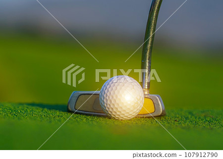 Golf ball and golf club on green in a beautiful golf course with morning sunshine. 107912790