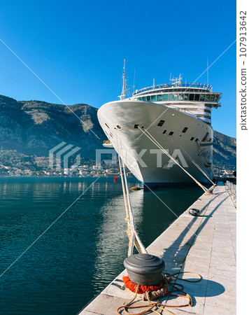 Large ship is moored to the mooring bollards at the pier against the backdrop of the mountains Large ship is moored to the mooring bollards at the pier against the backdrop of the mountains 107913642