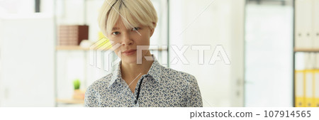 Serious woman with short dyed blonde hair holds clipboard 107914565