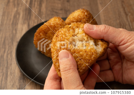 Grilled rice balls on hand, split Grilled rice balls on hand, split 107915380