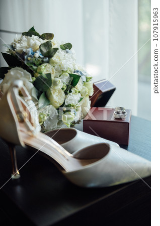 Wedding set of the bride. Shoes and rings lie next to the wedding bouquet Wedding set of the bride. Shoes and rings lie next to the wedding bouquet 107915963