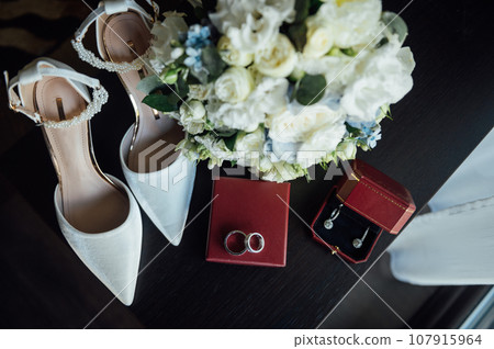 Wedding set of the bride. Shoes and rings lie next to the wedding bouquet Wedding set of the bride. Shoes and rings lie next to the wedding bouquet 107915964