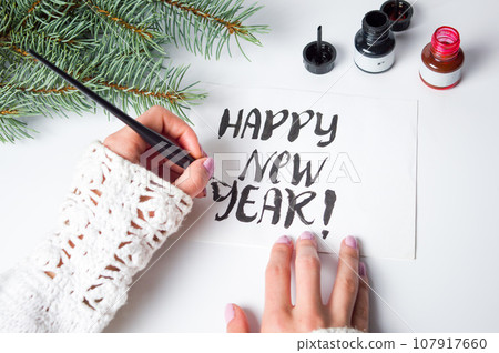 Girl writing Happy new year calligraphy card Girl writing Happy new year calligraphy card 107917660