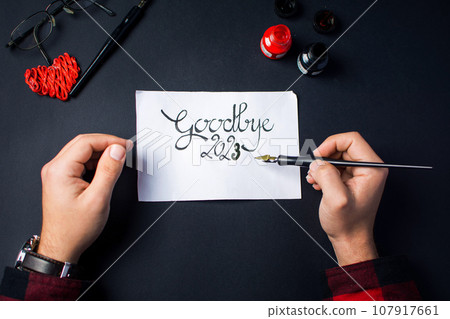 Man writing Goodbye 2023 New Year note Man writing Goodbye 2023 New Year note 107917661