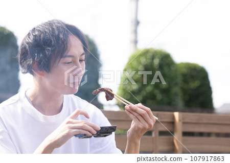 一名男子在燒烤時享用烤肉 107917863