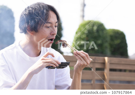 一名男子在燒烤時享用烤肉 107917864