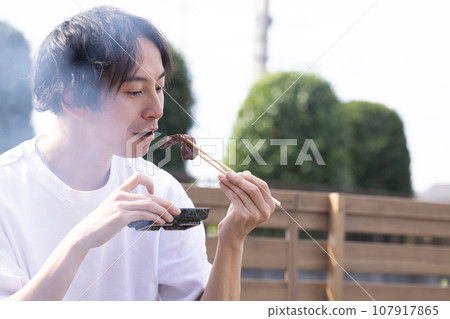 一名男子在燒烤時享用烤肉 107917865