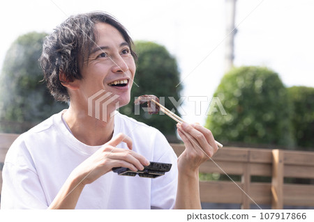 一名男子在燒烤時享用烤肉 一名男子在燒烤時享用烤肉 107917866