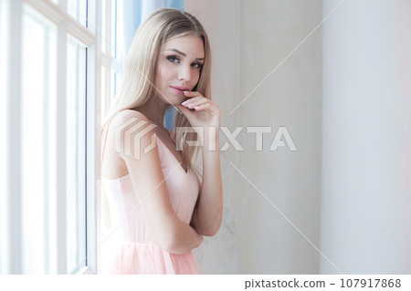 Beautiful young smiling woman with long blonde hair posing. Enjoying time at home 107917868