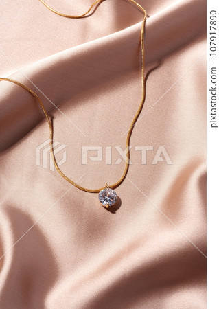 Golden necklace on silk texrtile background close up Golden necklace on silk texrtile background close up 107917890