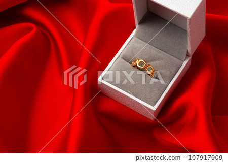 Golden ring in a jewelry box on red silk background 107917909