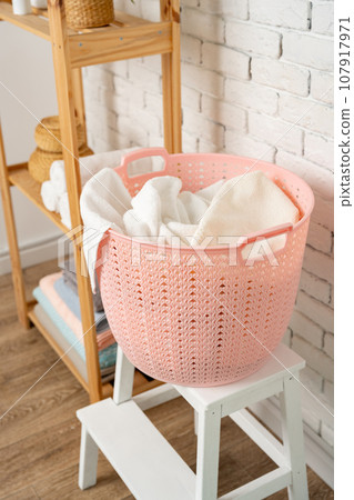 Pink plastic laundry basket in a bathroom 107917971