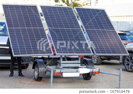 Large solar panels on a trailer hitch in a car parking lot. Large solar panels on a trailer hitch in a car parking lot. 107918476
