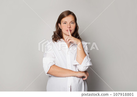 Girl or boy? Pregnant woman holding her finger near her lips and showing shhh gesture.  107918801