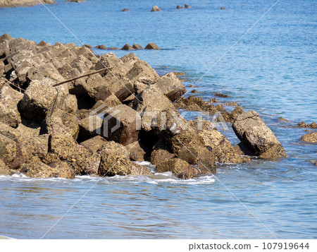 A wave-dissipating block on a calm coast. A wave-dissipating block on a calm coast. 107919644