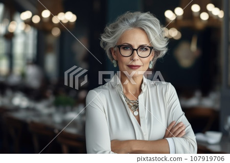 An elderly woman with glasses and gray hair who runs a restaurant 107919706
