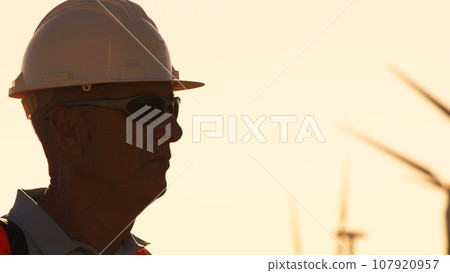 Silhouette of an engineer with white helmet in wind farm 107920957