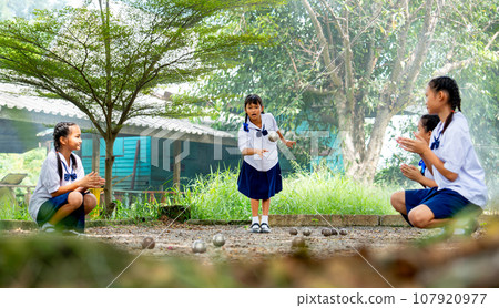Group of little Asian girl enjoy to play petanque in area of sand yard as sport field action cheer Group of little Asian girl enjoy to play petanque in area of sand yard as sport field action cheer 107920977