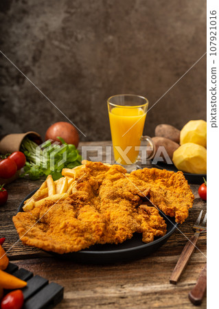 Golden bown crispy pork with fried fries in a black plate with helthy vegetables on the wooden table 107921016