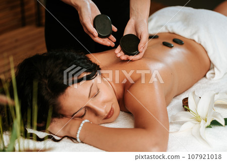 Beautiful young woman in the massage salon with brown curly hair and healthy skin. Masseur and patient concept. Beautiful young woman in the massage salon with brown curly hair and healthy skin. Masseur and patient concept. 107921018