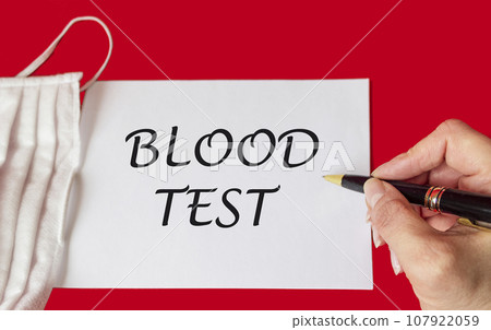 Medical concept. The phrase BLOOD TEST is written by a female hand on a notebook, next to Medical concept. The phrase BLOOD TEST is written by a female hand on a notebook, next to 107922059
