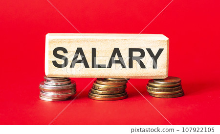 Salary text written on a wooden block with folded coins on a red background Salary text written on a wooden block with folded coins on a red background 107922105
