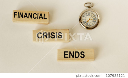 On wooden blocks the text End of crisis and a clock on a white background On wooden blocks the text End of crisis and a clock on a white background 107922121