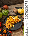 French fries served on black plate and wooden table 107923078