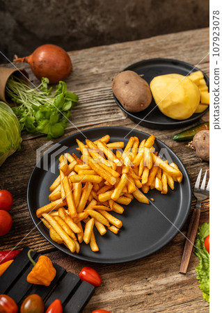 French fries served on black plate and wooden table French fries served on black plate and wooden table 107923078