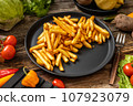 French fries served on black plate and wooden table 107923079