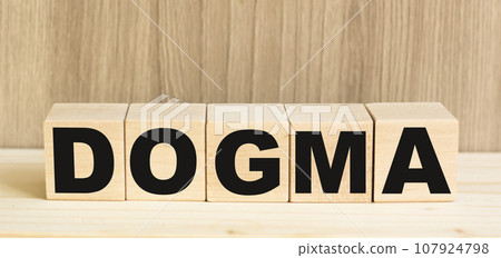 Word DOGMA on concept from wooden blocks on brown background Word DOGMA on concept from wooden blocks on brown background 107924798