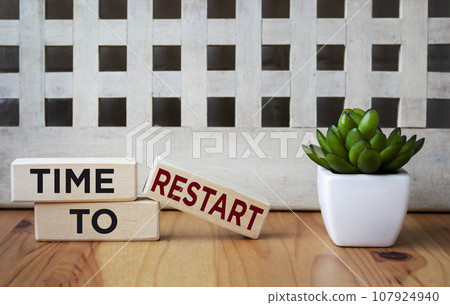 On a wooden background three wooden blocks with the text TIME TO RESTART 107924940